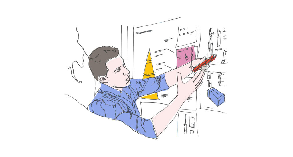 A person in a blue shirt holds a red pen, drawing on a wall with colorful notes and drawings. 